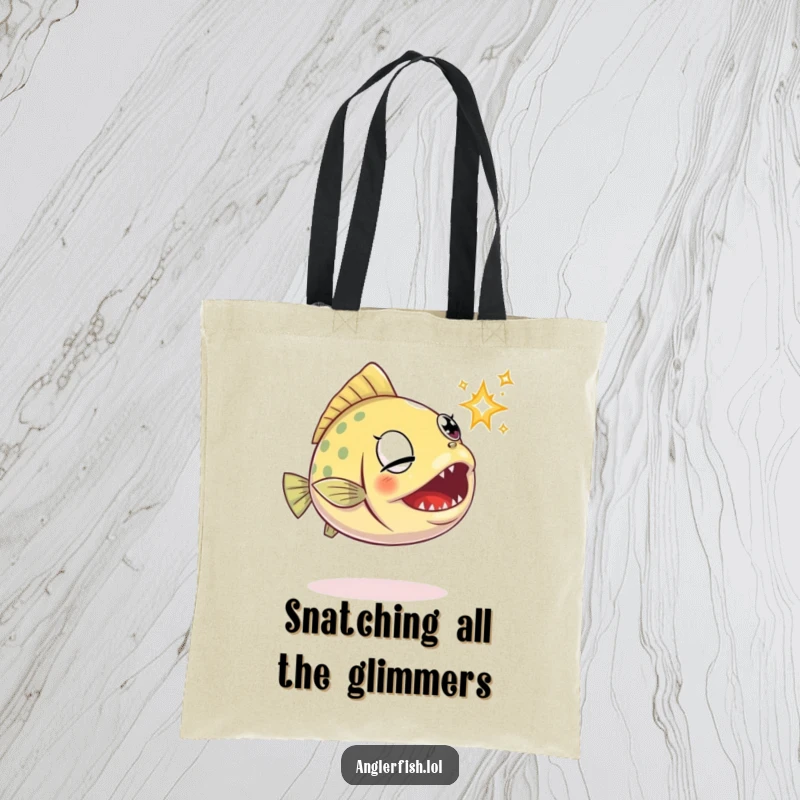 Funny anglerfish tote bag features a determined anglerfish attempting to grab a glimmering sparkle with its open jaws.